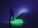 Silueta de un adulto pisando el primer peldaño iluminado en verde de una escalera oscura: empezar a aprender inglés desde cero